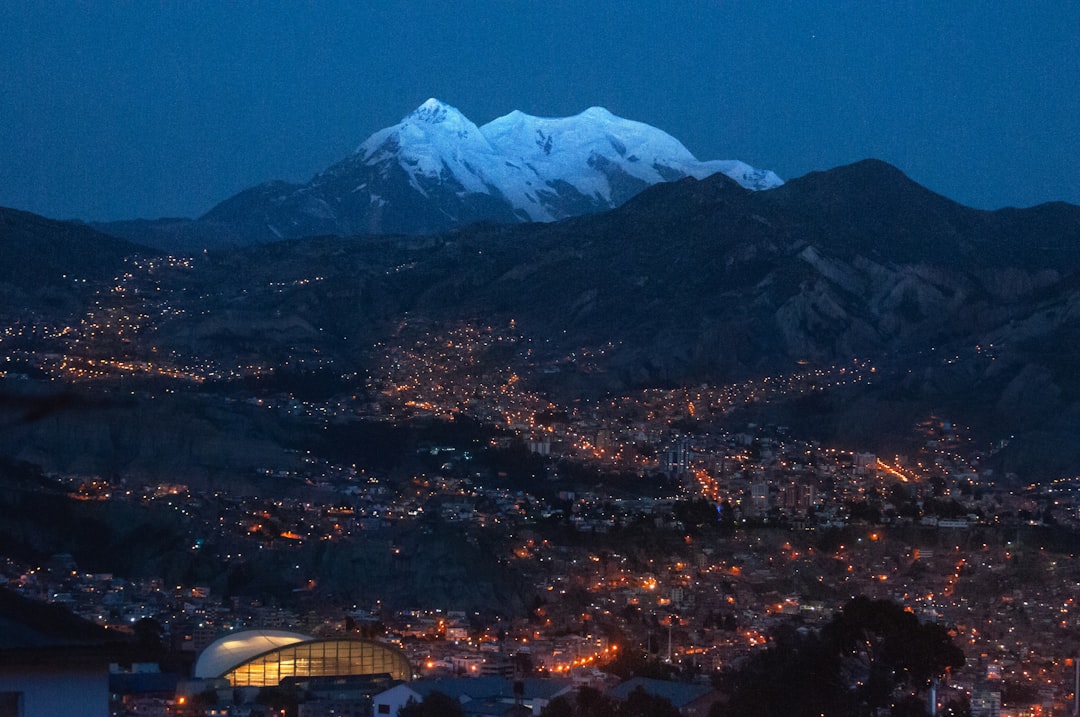 Mount Illimani, the guardian of La Paz, Bolivia. Its peaks barely illuminated by the last rays of daylight. The city already lit up.